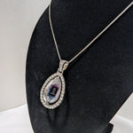Customizable double-sided teardrop shaped silver rhinestone pendant with a silver necklace on a black stand
