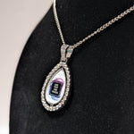 Customizable double-sided teardrop shaped silver rhinestone pendant with a silver necklace on a black stand