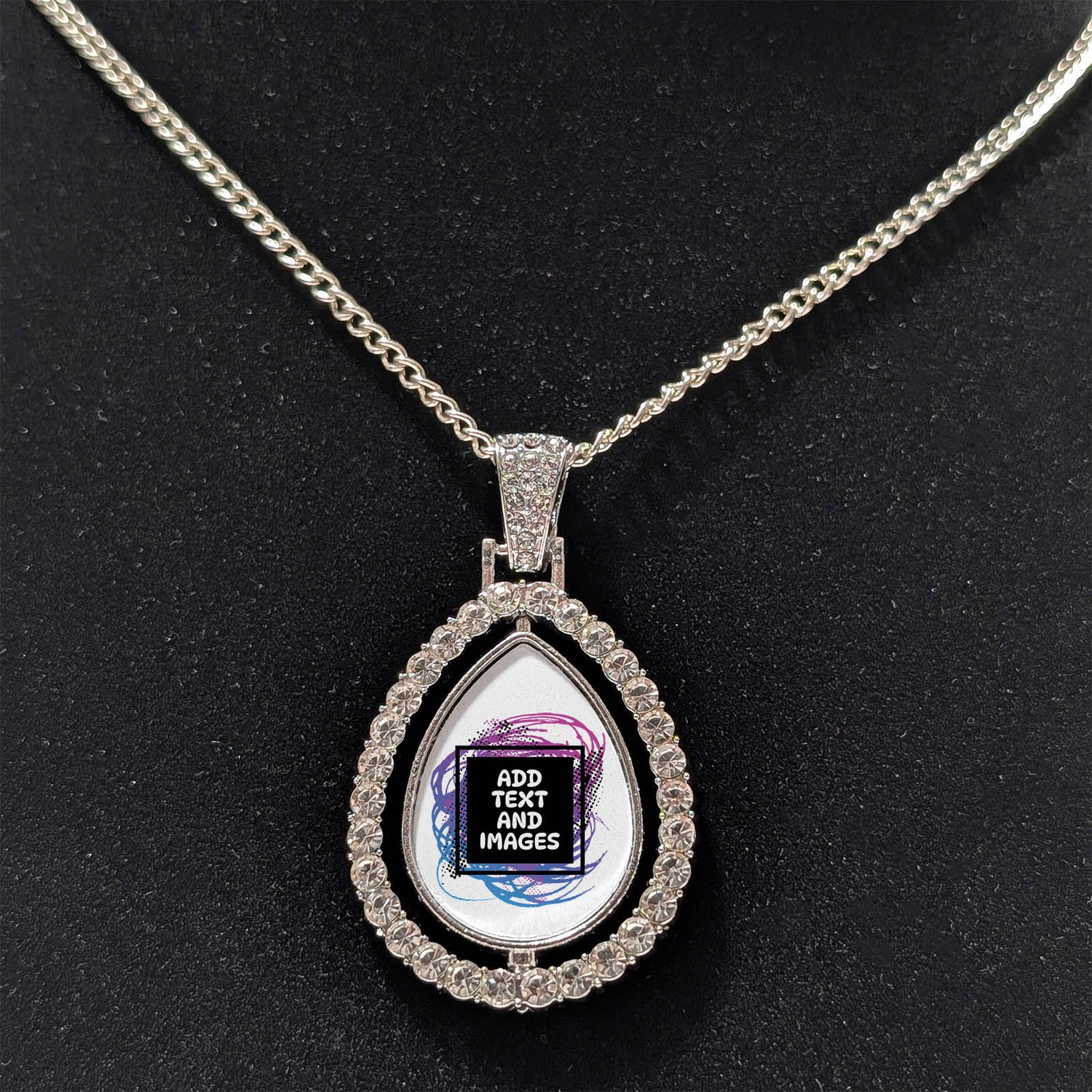 Customizable double-sided teardrop shaped silver rhinestone pendant with a silver necklace on a black stand