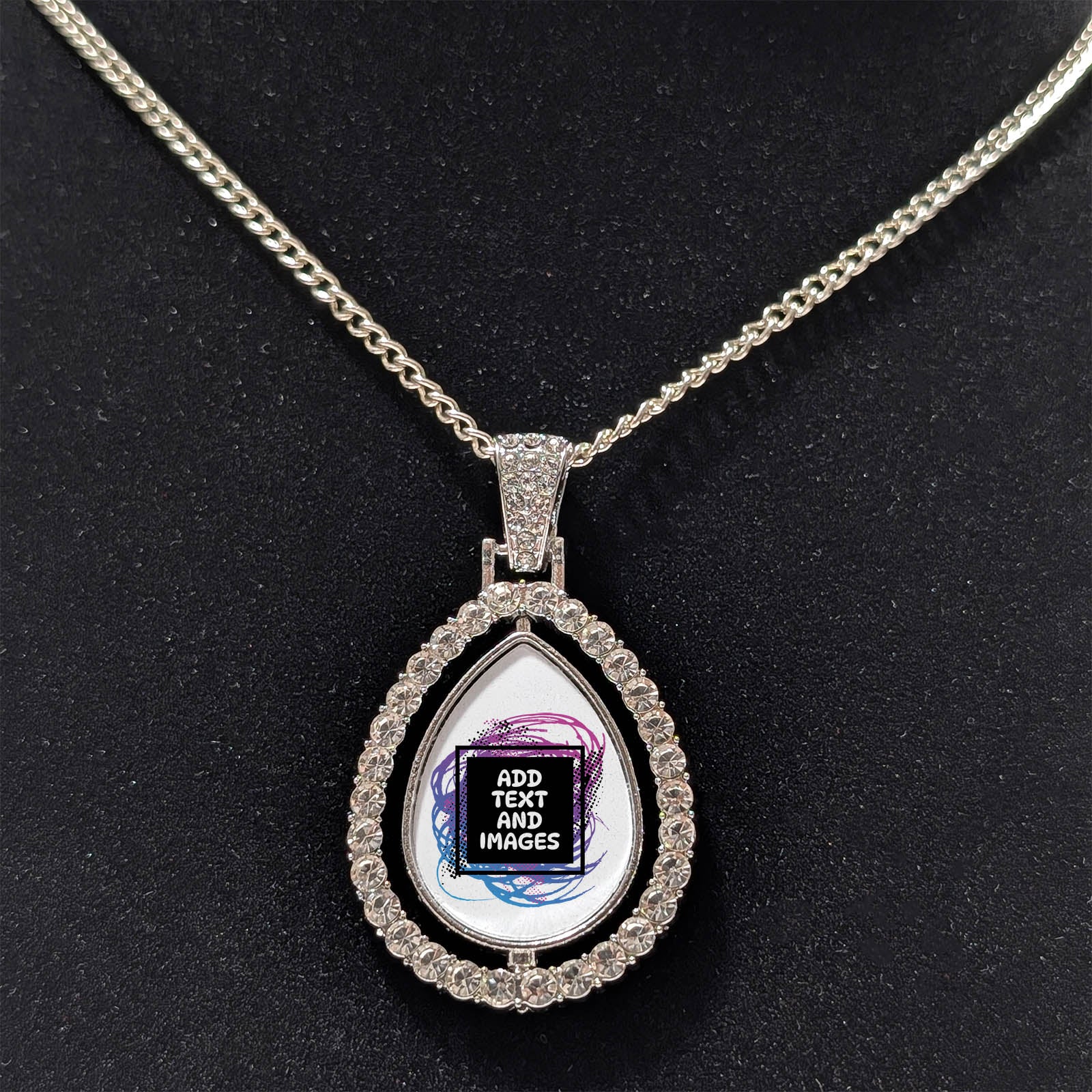 Customizable double-sided teardrop shaped silver rhinestone pendant with a silver necklace on a black stand